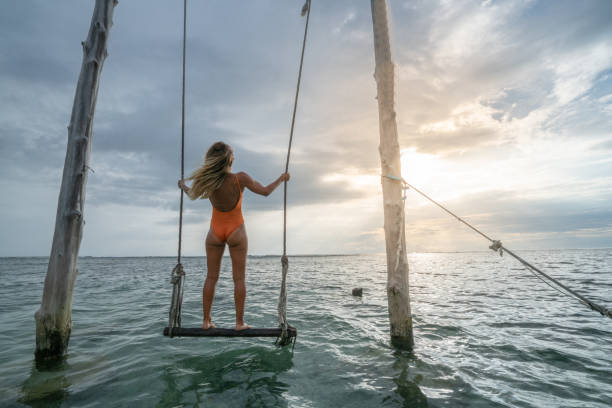 Young woman swinging over the sea, beautiful and idyllic landscape. People travel vacations concept. Young woman swinging over the sea, beautiful and idyllic landscape. People travel vacations concept. gili trawangan stock pictures, royalty-free photos & images