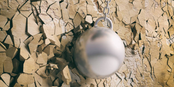 istock Wrecking ball hitting and breaking a golden wall. 3d illustration 1048647876