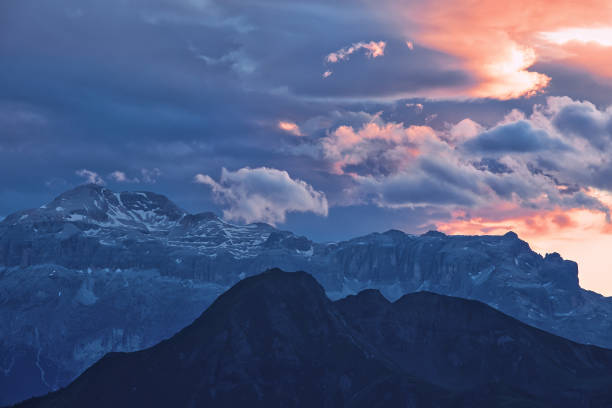 istock Beautiful mountain peaks covered by colored clouds at sunset, mountain landscape background 1048663800
