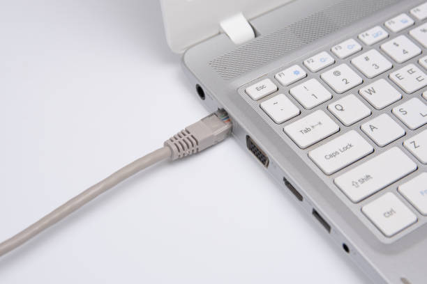 istock Closeup connection cable network connection to a Lan port of a laptop on white table, concept computer connection. 1048663860