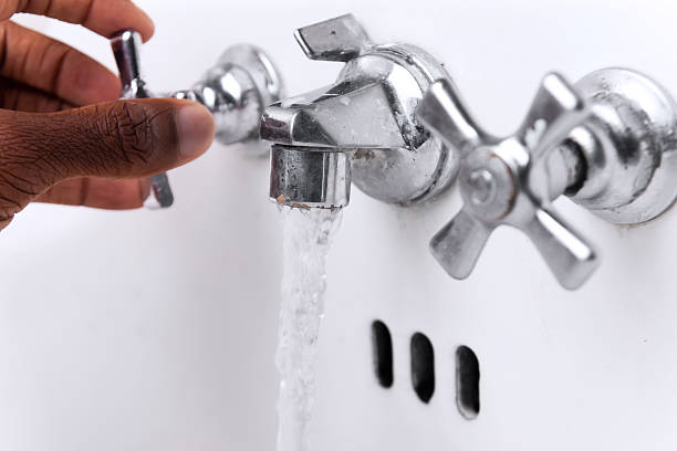 Hand on faucet with running water