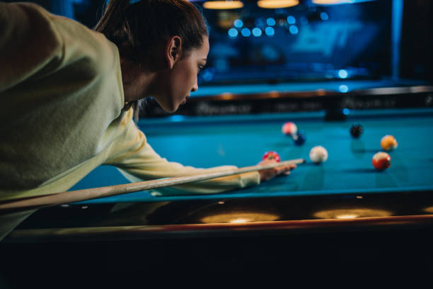 istock Young woman concentrating while playing billiard in a pool hall. 1048680650