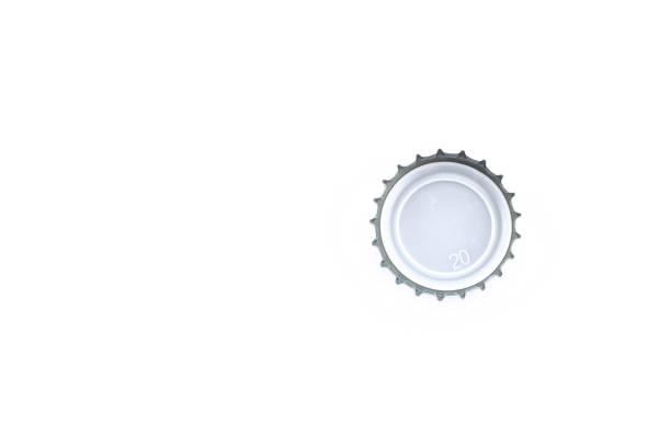 Three bottle tops stacked upon one another, resting on a metal table.  Shallow depth of field.