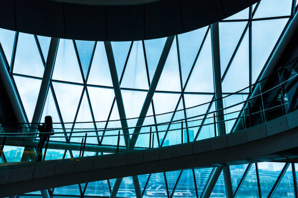 Abstract modern architecture and silhouette of woman on spiral staircase Wide angle color image depicting ultra modern contemporary interior architecture in City Hall (a public building in London that is open to the public) in London, UK. The silhouette of a lone woman is visible as she walks down the modern spiral staircase. In the background we can see some of the skyscrapers that dominate the skyline of London. Lots of room for copy space. gla building stock pictures, royalty-free photos & images