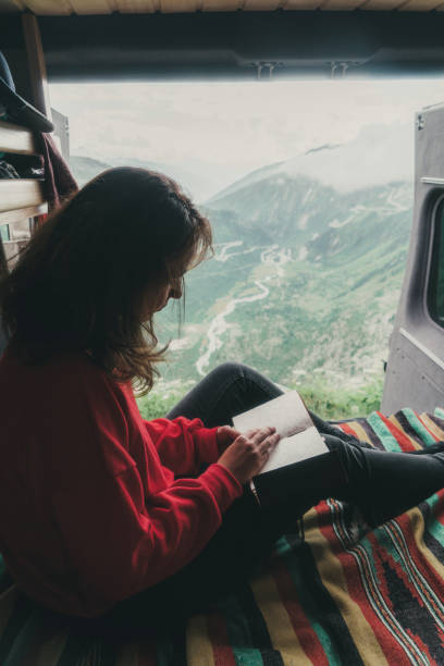 istock Woman reading book in camper van with view on Furka Pass 1048689668