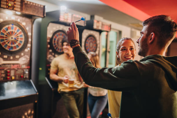Happy couple having fun while playing darts in a pub.