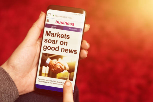 istock Hand holds phone displaying message: Markets soar on good news 1048711436