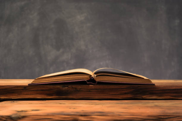 istock Old book on a old oak wooden table. Beautiful dark background. 1048712218