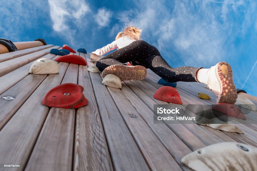 Low Angle View of Girl Climbing Rock Wall Outdoors Climbing Stock Photo