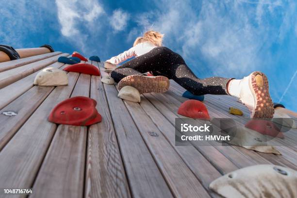 Low Angle View Of Girl Climbing Rock Wall Outdoors Stock Photo - Download Image Now - Climbing, Wall - Building Feature, Surrounding Wall