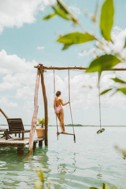 istock Woman sitting on a swing at a lagoon 1048717338