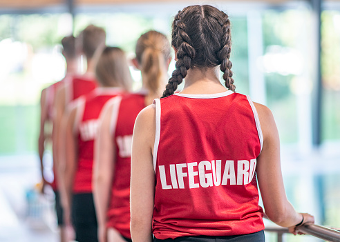A group of lifeguards are standing in a line with their packs towards the camera. 