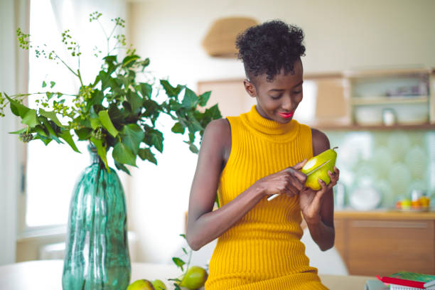 istock Young woman is eating a pear at home - 1048717486