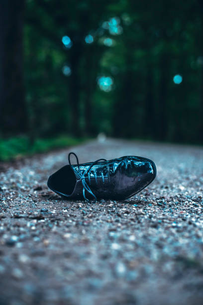 Lost shoe on road in dark forest.