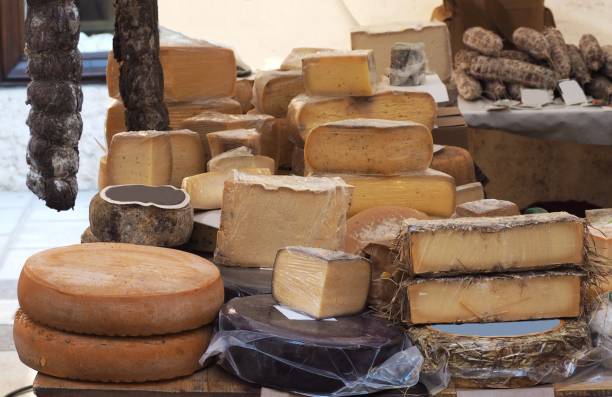 auswahl an italienischen bio-käse gemacht in den bergen weiden, teilweise mit kräutern, in einem ländlichen markt. salami auf dem hintergrund - piedmont cheese homemade italy stock-fotos und bilder