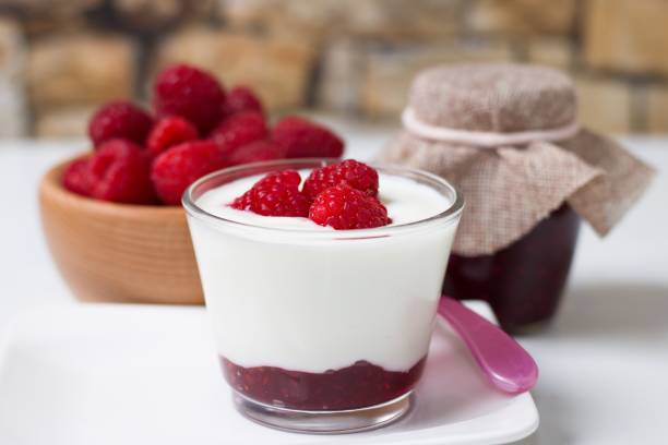 istock Glass cup of fresh white yogurt with raspberries 1048721656