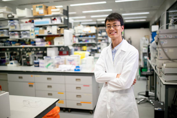 Medical Research Scientist A portrait of a Chinese medical scientist full of pride in his research laboratory, he is looking and smiling at the camera. male chinese student stock pictures, royalty-free photos & images