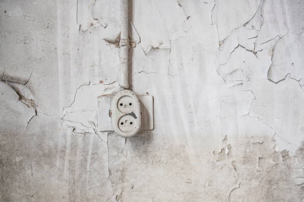 Wall socekt in an abandoned school building interior with damaged floors and ceilings