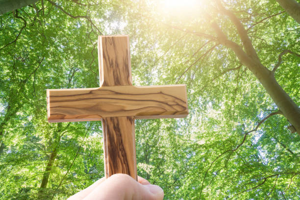 istock man holding wooden cross in the forest 1048736720