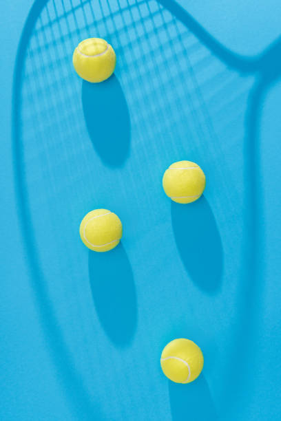 istock top view of arranged tennis balls and racket shadow on blue backdrop 1048741356