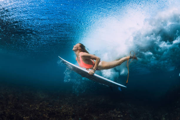 istock Attractive surfer woman dive underwater with under wave. 1048746248