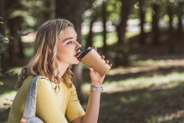 istock side view of young woman drinking coffee from disposable cup in park 1048746492