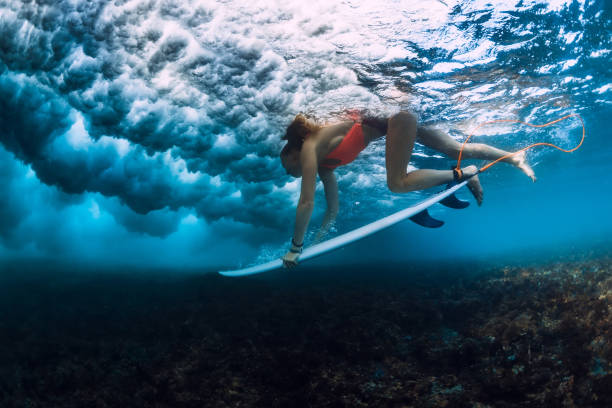 istock Professional surfer woman with surfboard make duck dive underwater with ocean wave. 1048746636