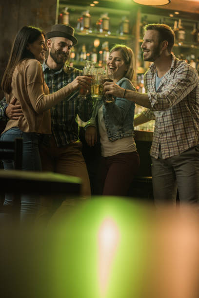 istock Two happy couples toasting with beer in a pub. 1048746842