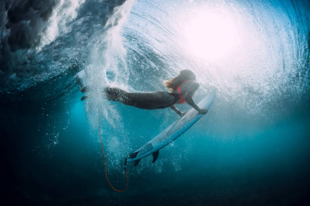 istock Surfer girl with surfboard dive underwater with under barrel ocean wave. 1048747084