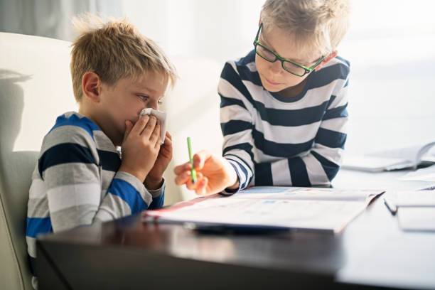 istock Little boy helping his sick brother to catch up with missed schoolwork 1048755952