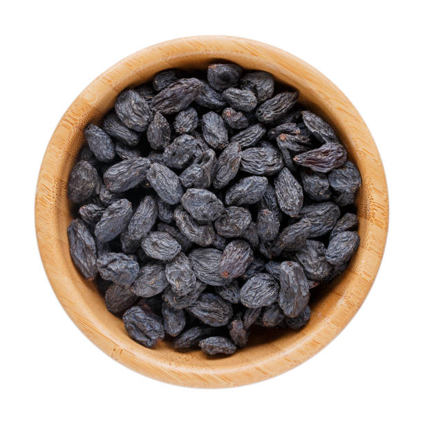 black raisins in wooden bowl isolated on white. dried fruits. top view - passas imagens e fotografias de stock