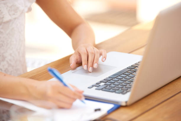 istock Close-up of woman hand making notes and using laptop 1048764002