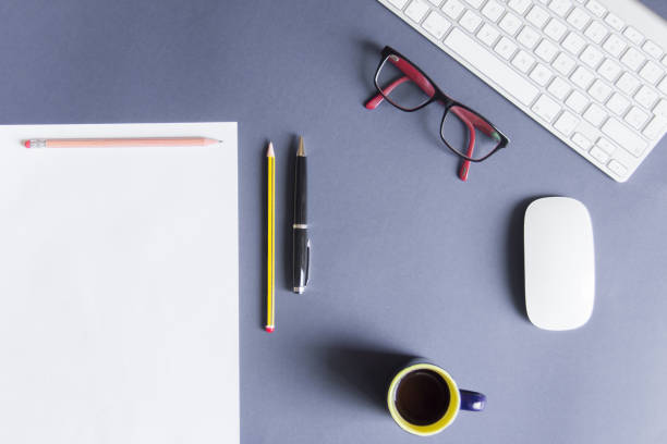 istock Blue desktop with blank sheet, pencil, cup of coffee, glasses, white mouse and white keyboard 1048771736