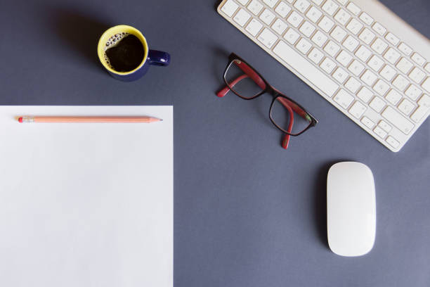 istock Blue desktop with blank sheet, pencil, cup of coffee, glasses, white mouse and white keyboard 1048771786