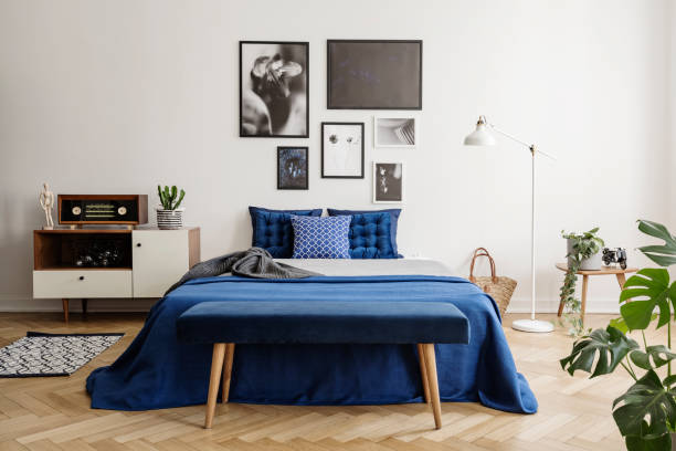 istock Upholstered bench on a wooden herringbone parquet in a bright and artistic bedroom interior with navy blue textiles 1048778410