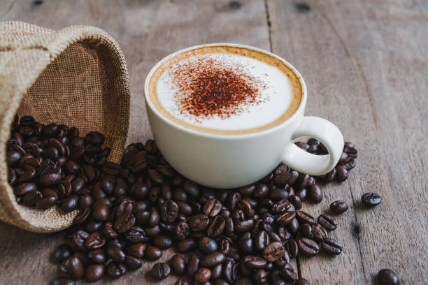 istock Coffee beans in the sack with a coffee cup on wooden table background. 1048784518
