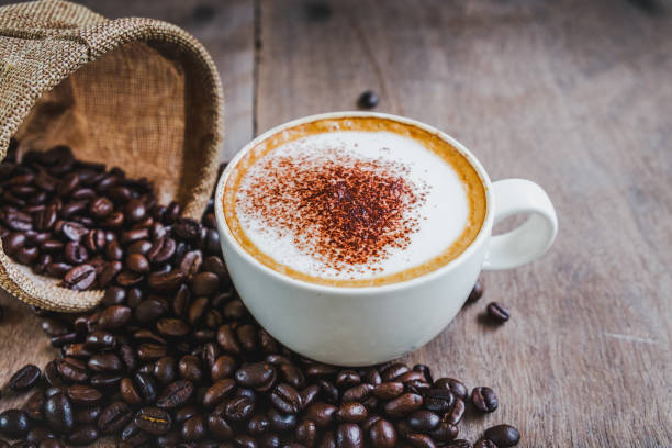 istock Coffee beans in the sack with a coffee cup on wooden table background. 1048784538