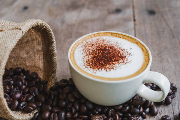 istock Coffee beans in the sack with a coffee cup on wooden table background. 1048784542