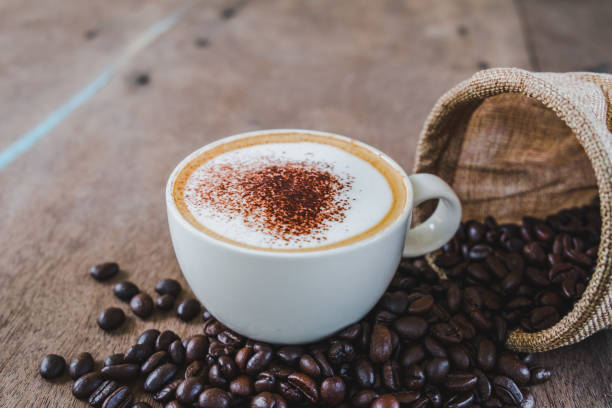 istock Coffee beans in the sack with a coffee cup on wooden table background. 1048784702