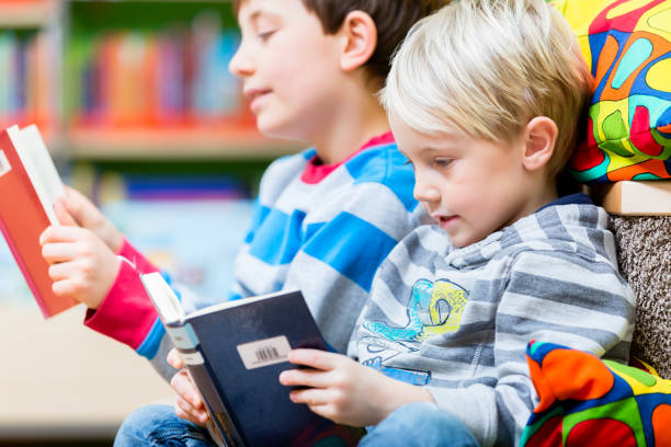 istock Two boys reading books in the library 1048787304