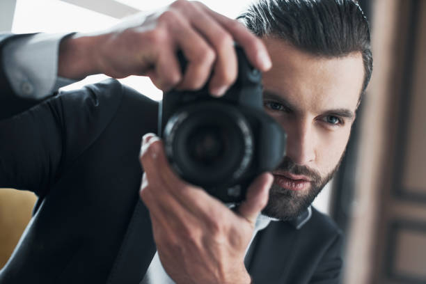 istock Stylish businessman is taking photo at proffesional camera 1048789794