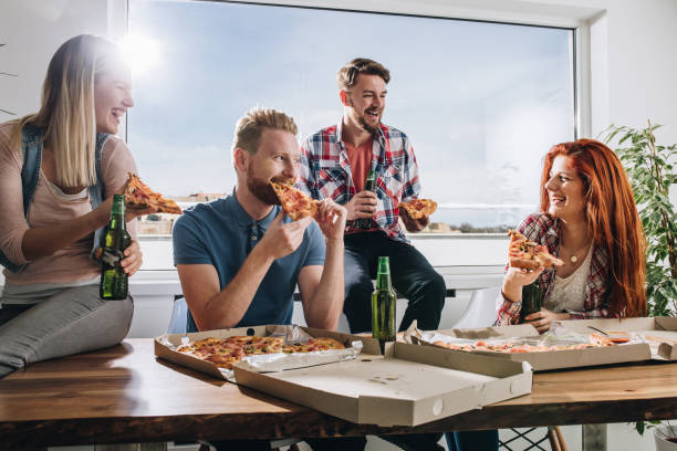 istock Happy friends having fun while eating pizza and drinking beer. 1048790762