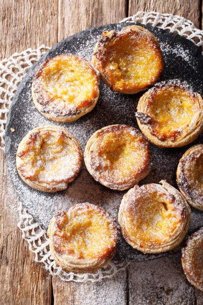 istock Pastel de nata with sugar powder close-up on the table. vertical top view 1048793768