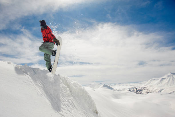 istock Jumping snowboarder keeping hand on the snowboard on blue sky background 1048803084