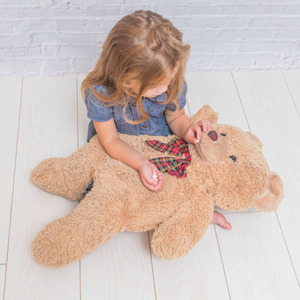 istock child treats a toy bear, a pill in front of a white brick wall 1048807048
