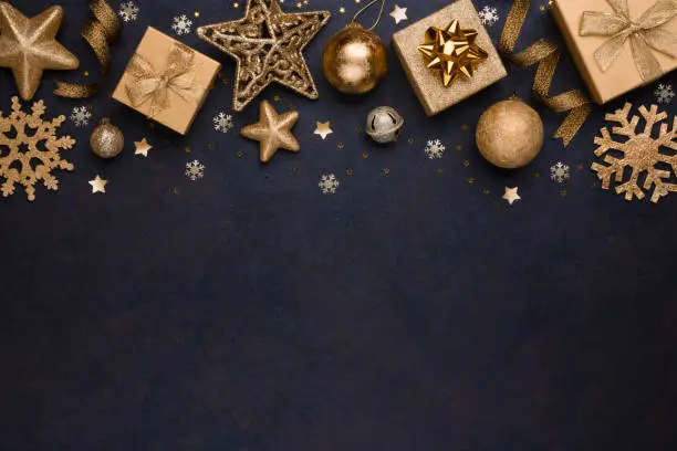 Photo of Golden snowflakes, gifts, christmas balls and stars on dark background