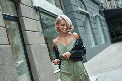 Fashion. Young stylish woman walking on the city street looking down laughing playful