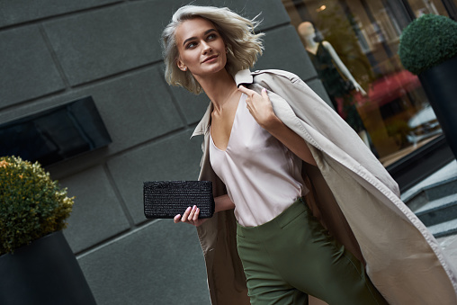 Fashion. Young stylish woman walking on the city street looking aside smiling happy close-up