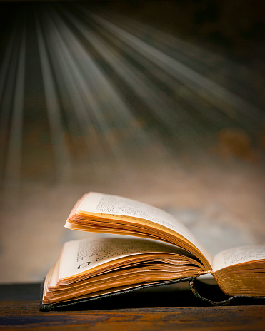 Open Christian bible with light rays streaming downward in background