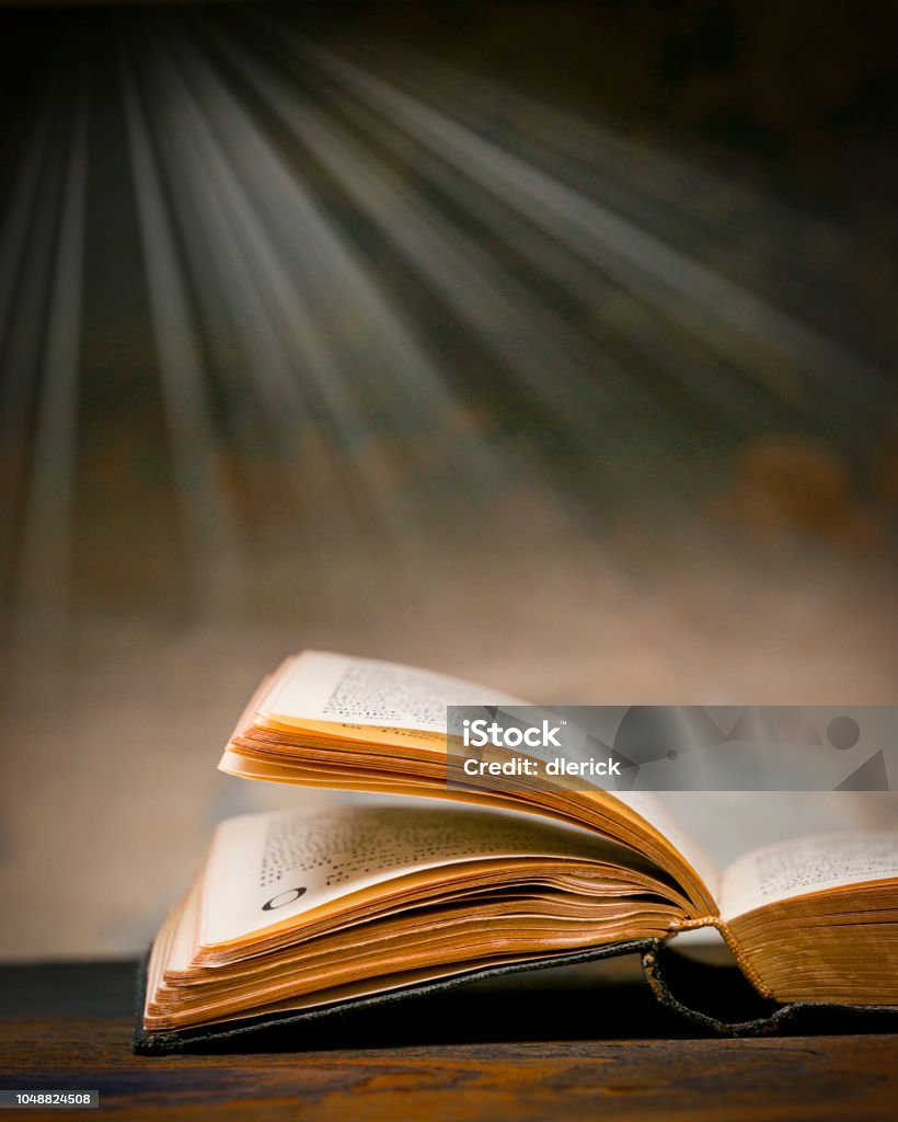 Christian Bible Open Christian bible with light rays streaming downward in background Bible Stock Photo